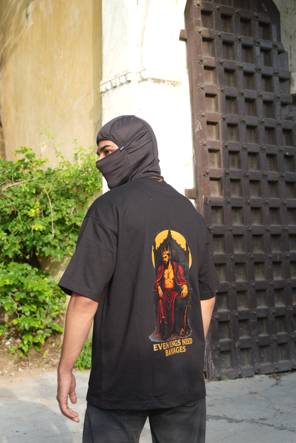 Person wearing a black hoodie with a graphic design on the back, standing outdoors.